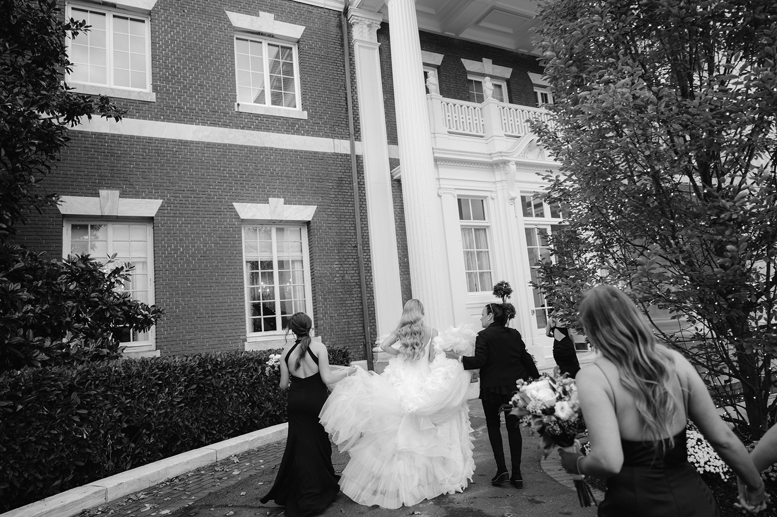 Bride and bridesmaids walking into the Bourne Mansion.