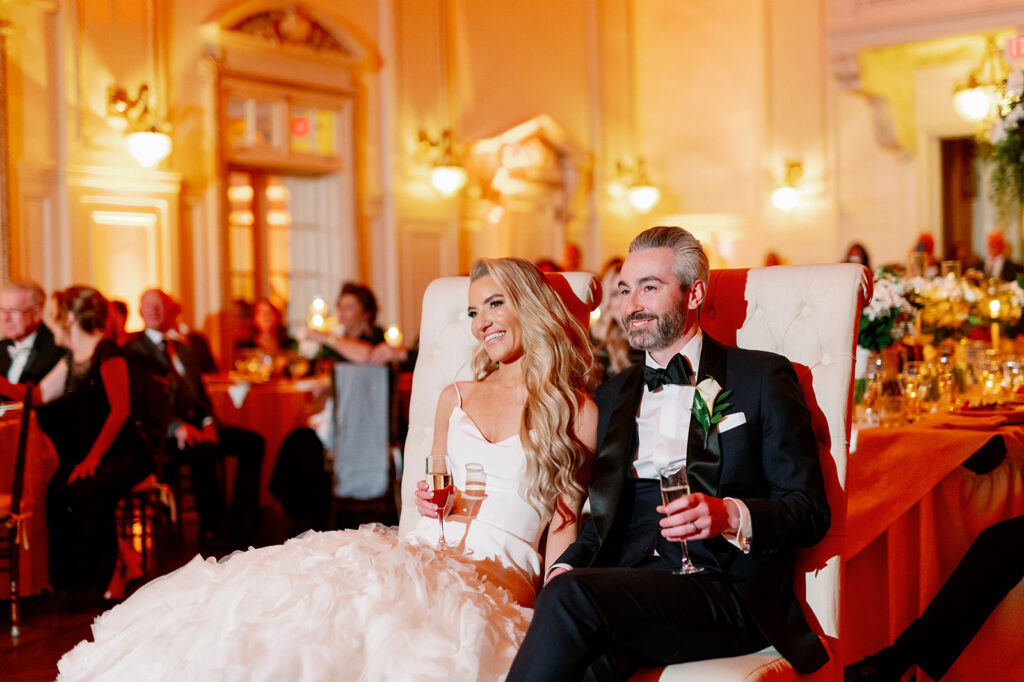 Bride and groom listening to speeches during their Bourne Mansion reception in the ballroom.