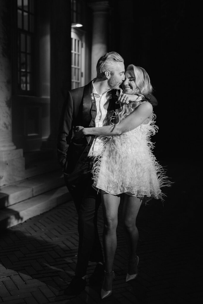 Bride and groom flash photo session outside Bourne Mansion with a short feathery reception dress.