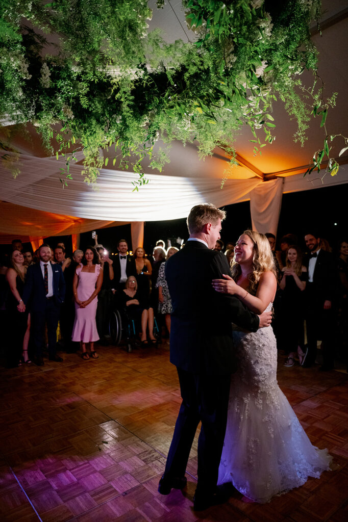 Bride and groom first dance under a stunning greenery installation.