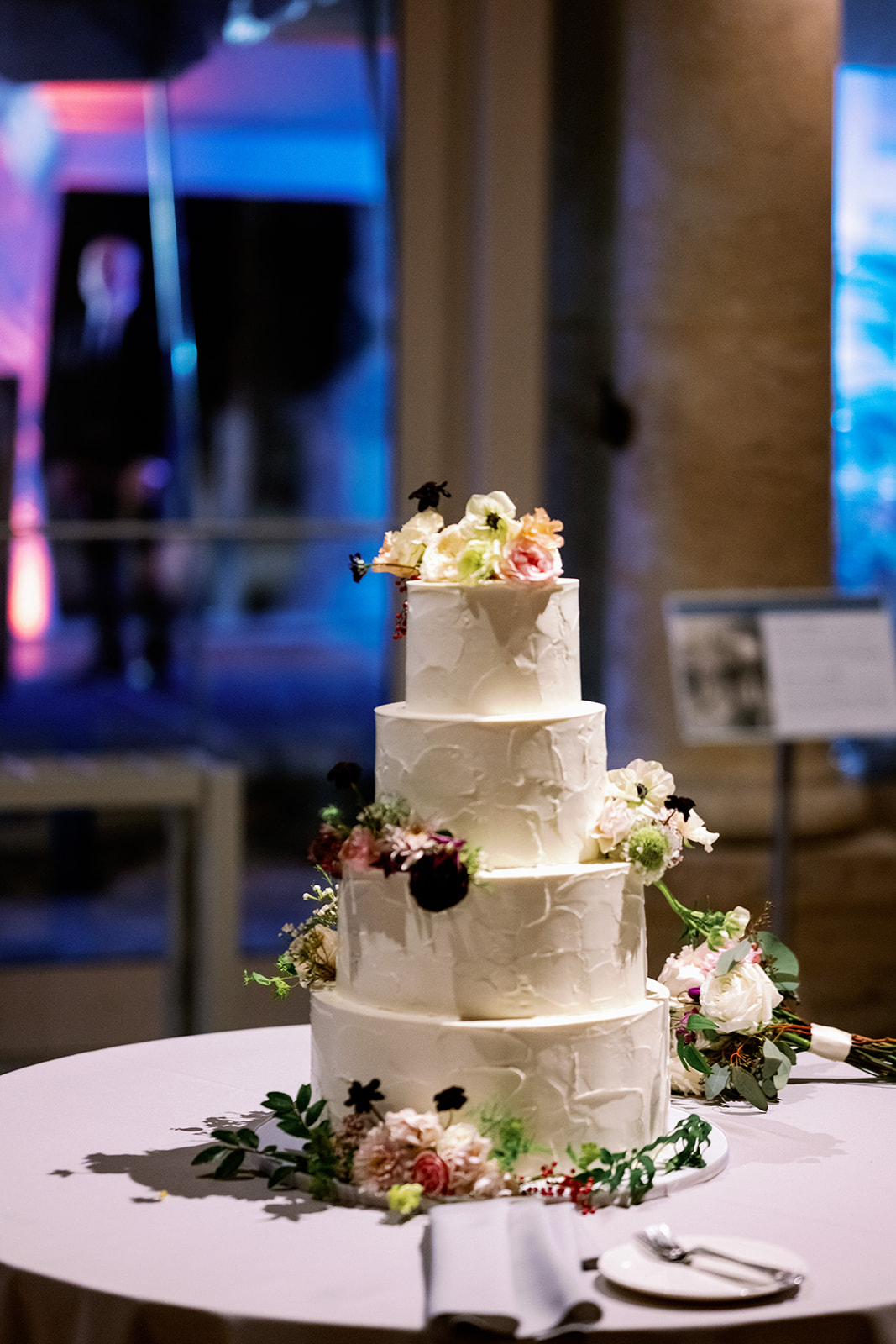 4-tier white wedding cake with flowers.