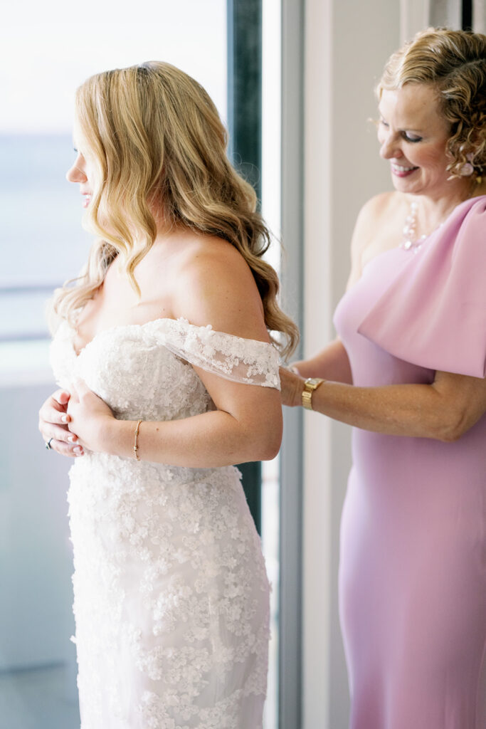 Bride's mom zipping up her wedding dress.