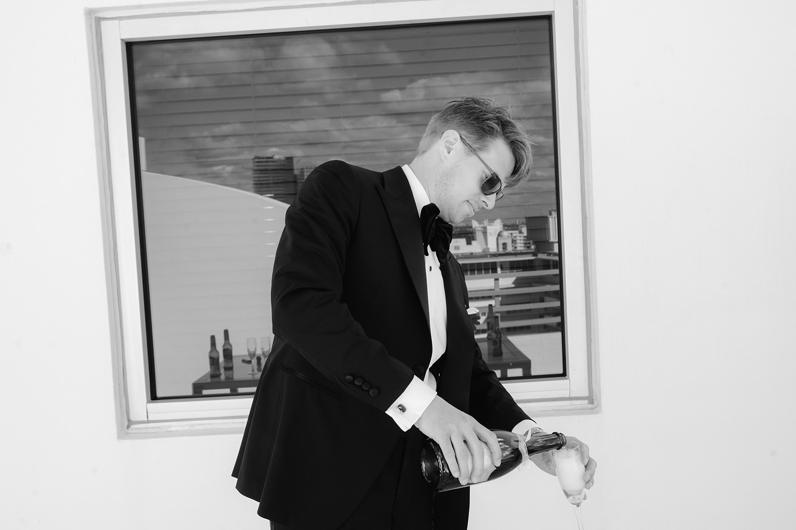 Groom wearing sunglasses and pouring a drink.