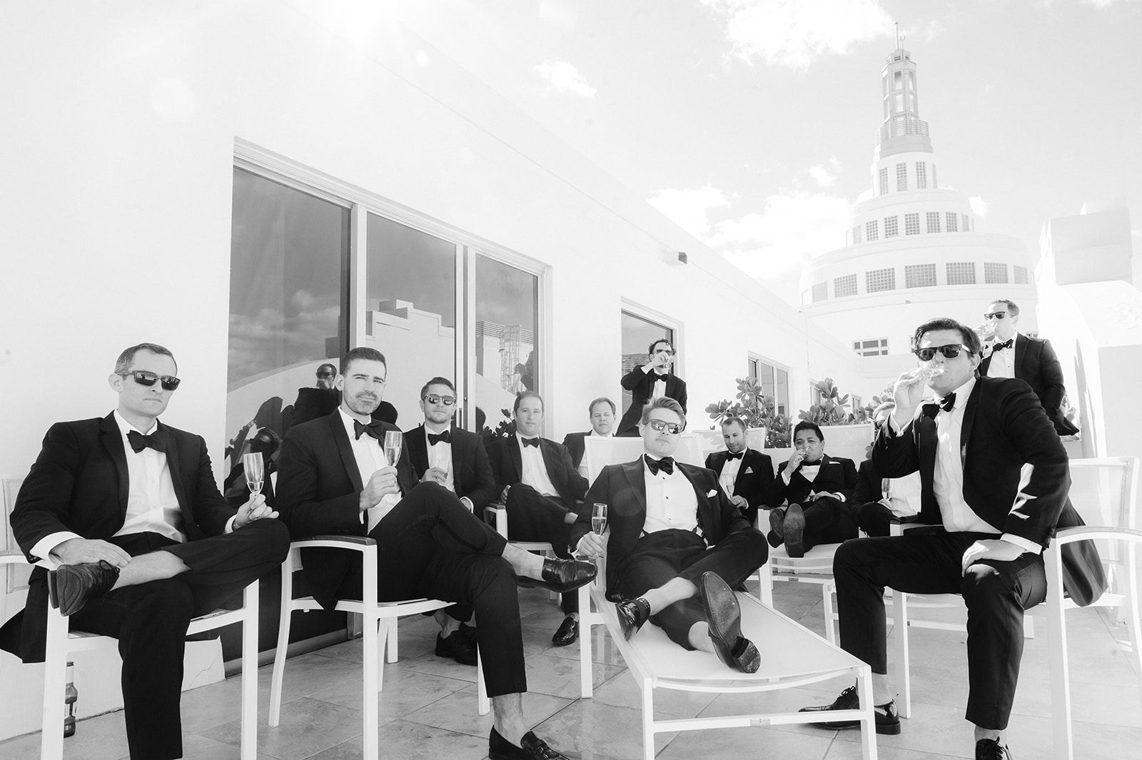 Groom and groomsmen wearing sunglasses and drinking champagne.