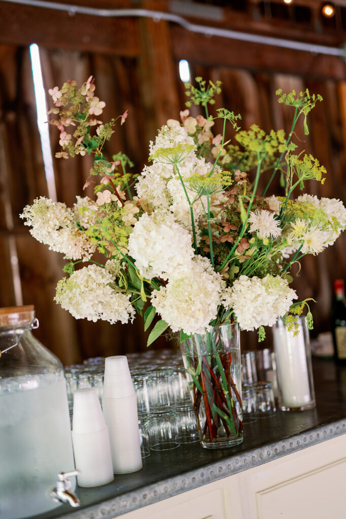 White floral arrangement in a glass vase on a bar. 