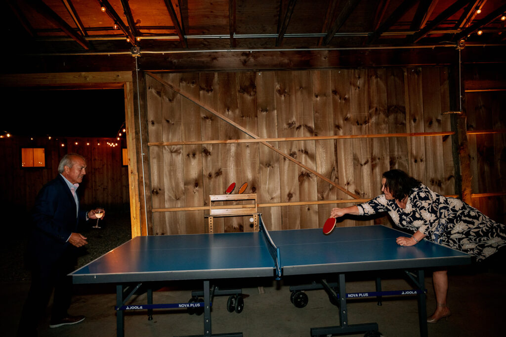Guests playing ping pong at a wedding rehearsal dinner at Troutbeck. 
