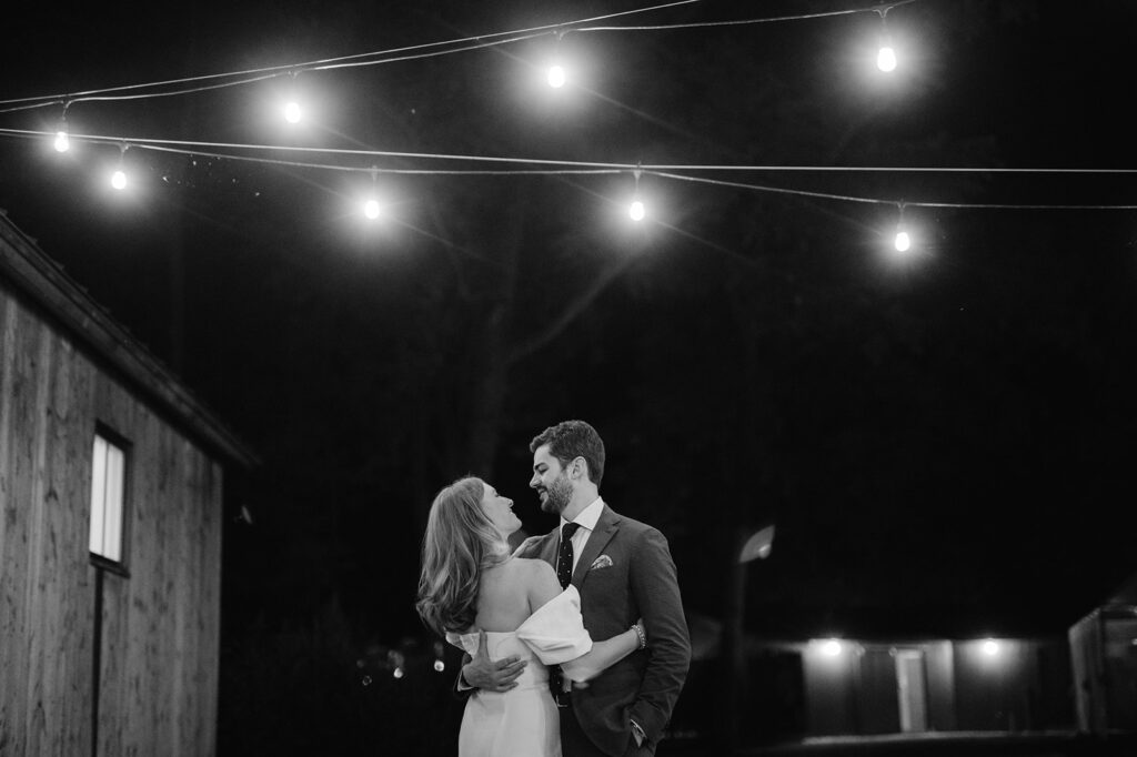 Bride and groom sharing an intimate moment under string lights at their rehearsal dinner.