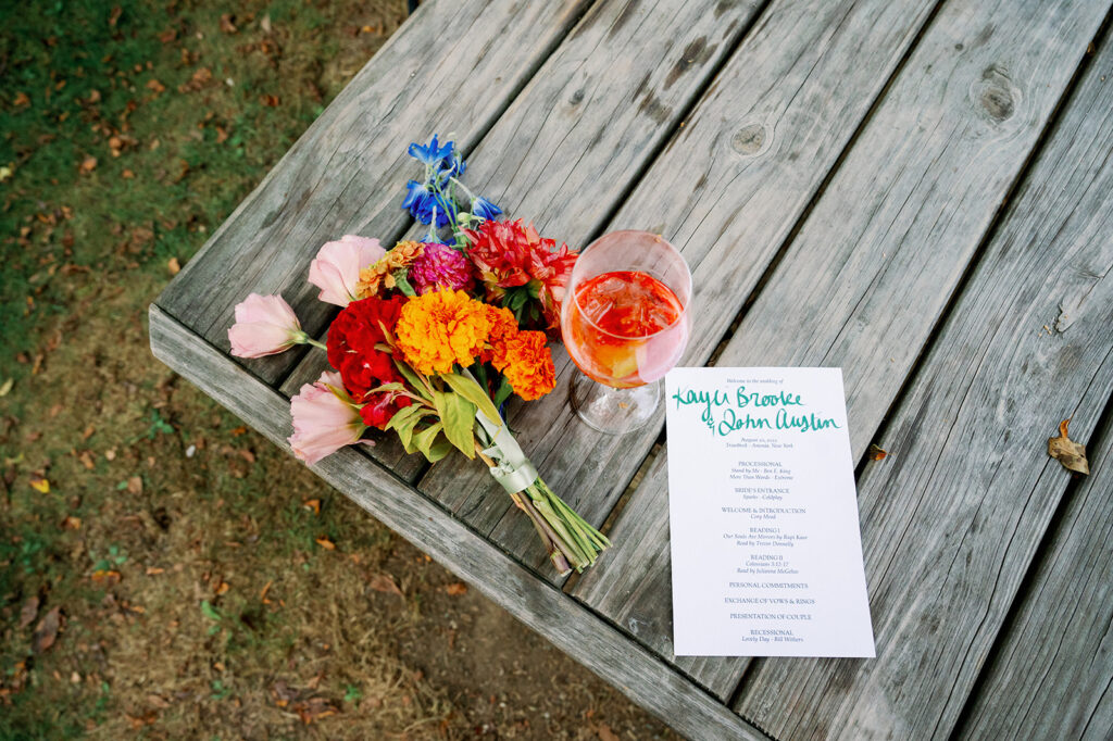 Wedding detail flat lay with the program, flowers and cocktail.