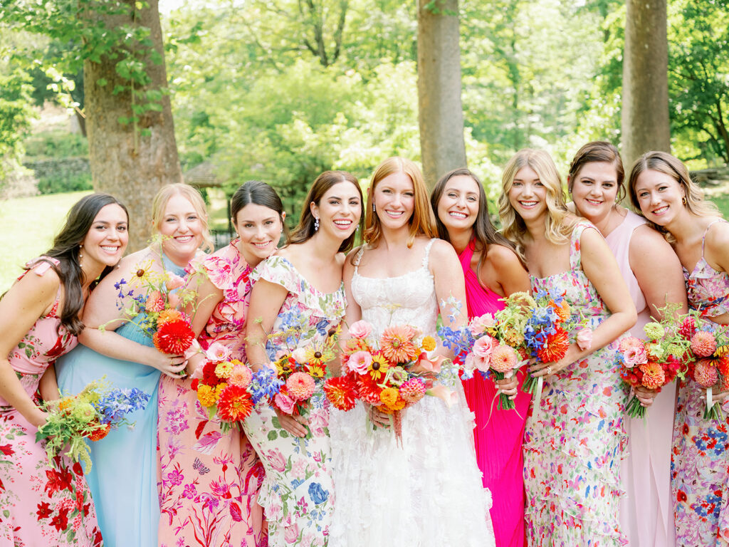 Bridal party portrait with mismatched vibrant pink and blue floral bridesmaid dresses. 