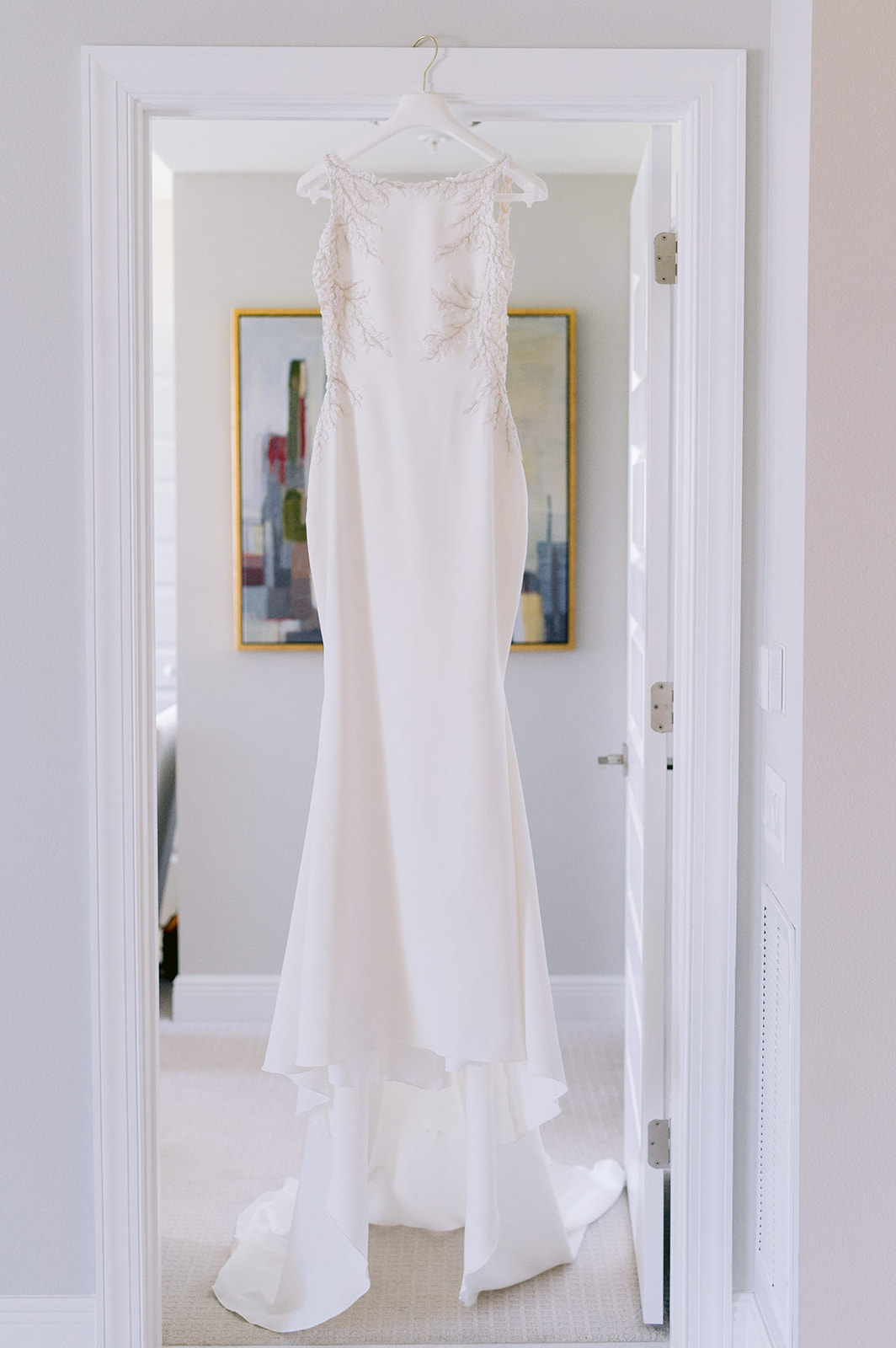 Wedding dress hanging from a white hanger. 