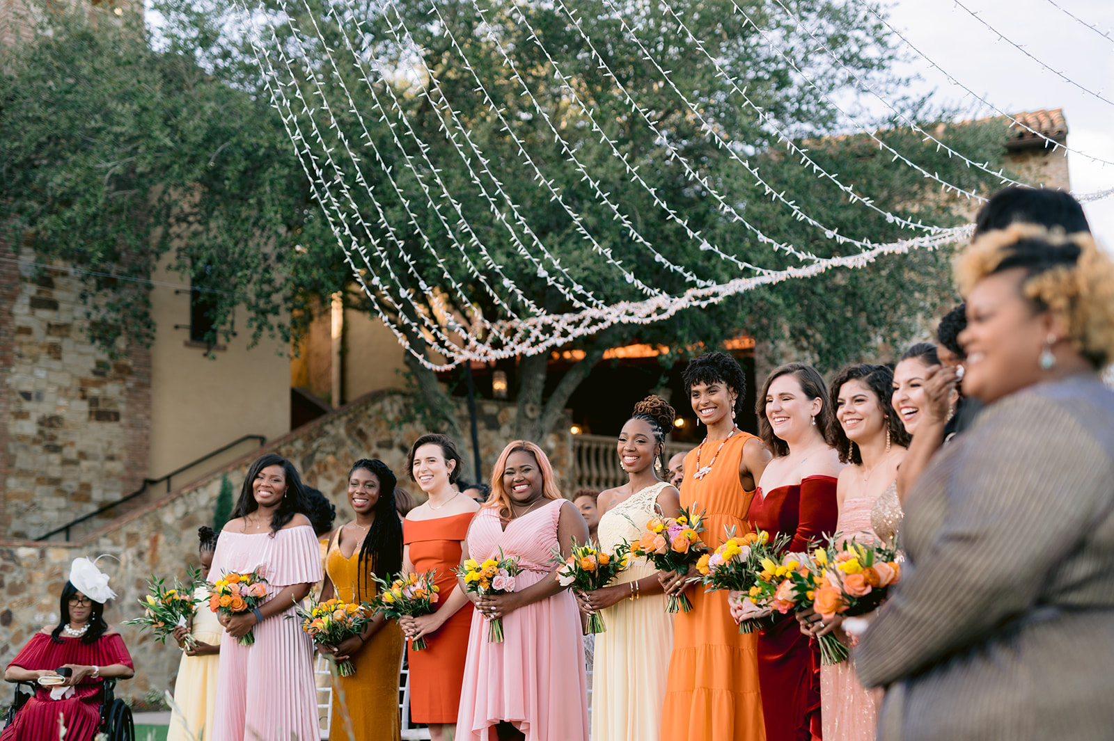 Bridesmaids in mismatched sunset colored dresses during the ceremony at Bella Collina.