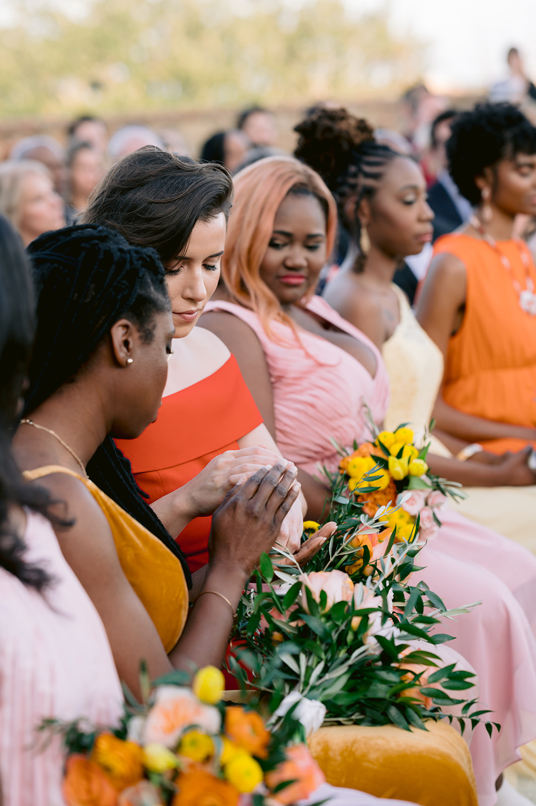 Sunset-hued bridesmaids participating in a ring-warming ceremony.