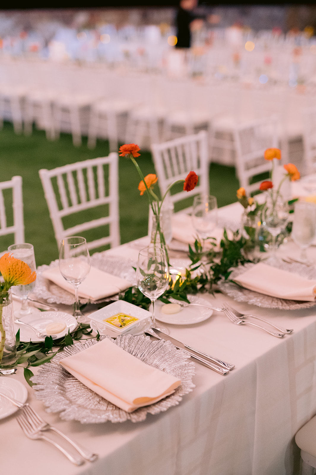 Romantic outdoor wedding reception table decor with simple poppy floral centerpieces.