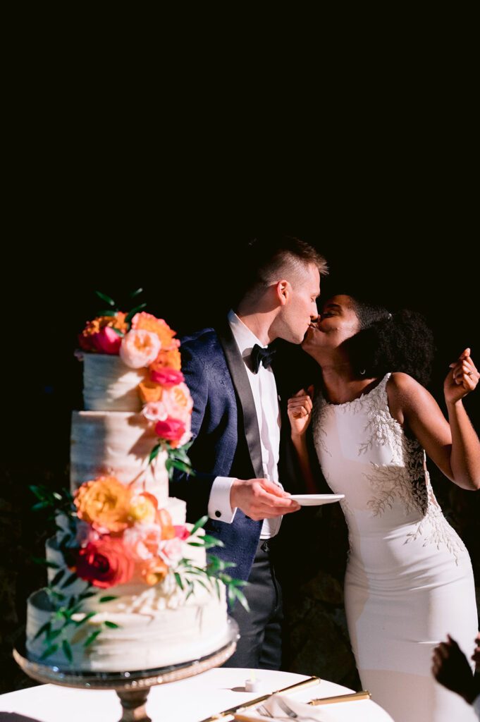 Bride and groom cake cutting kiss.