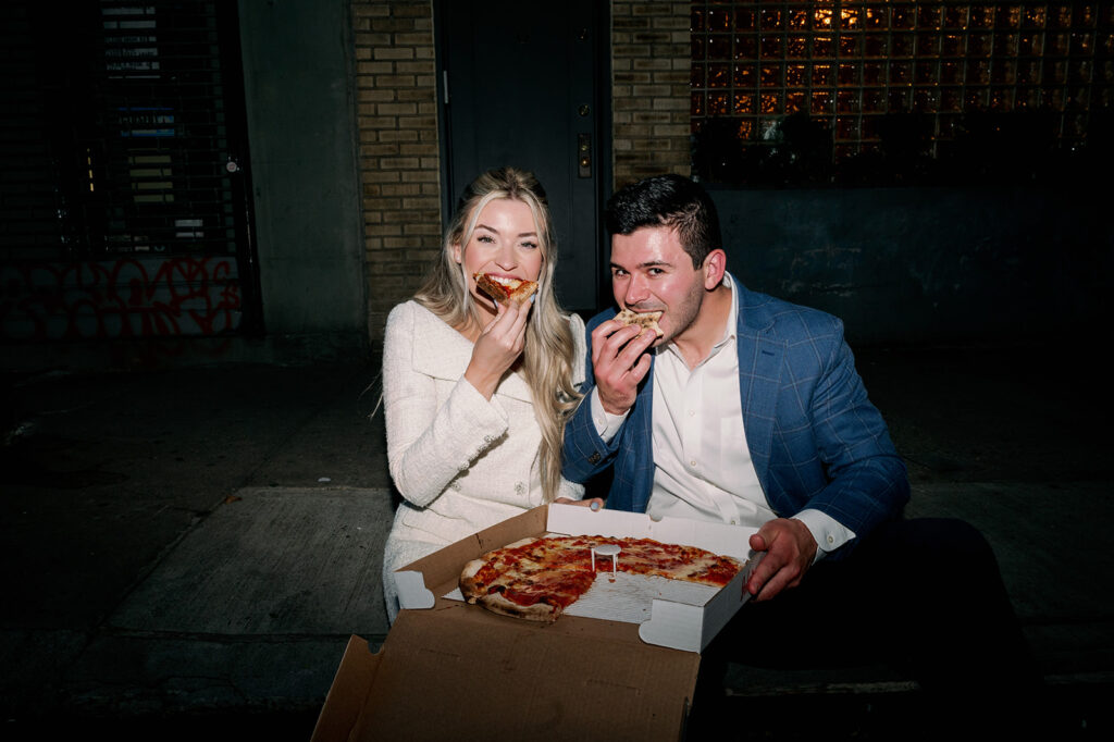 Couple eating pizza from John's Pizzeria during their city engagement photos in New York.