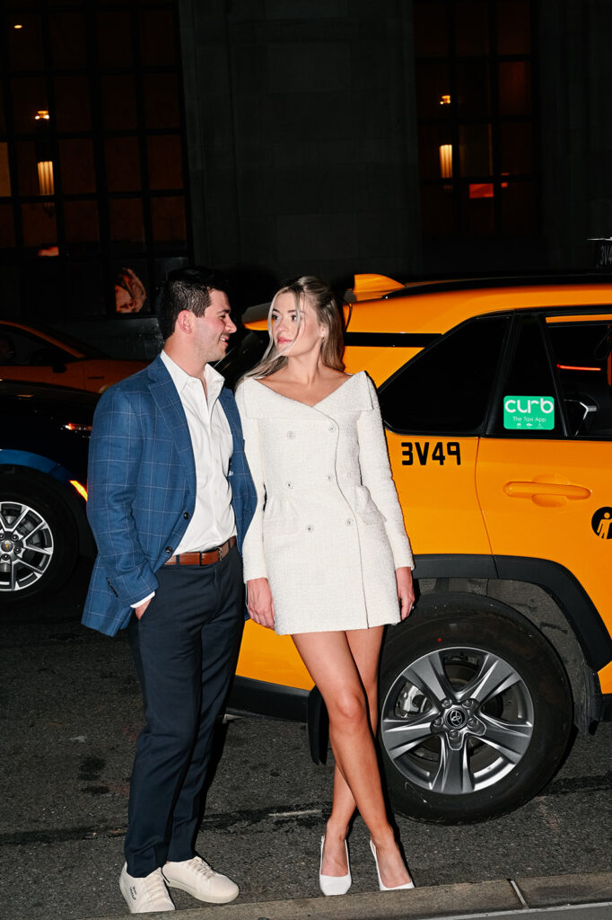 New York City couple posing in front of a taxi.