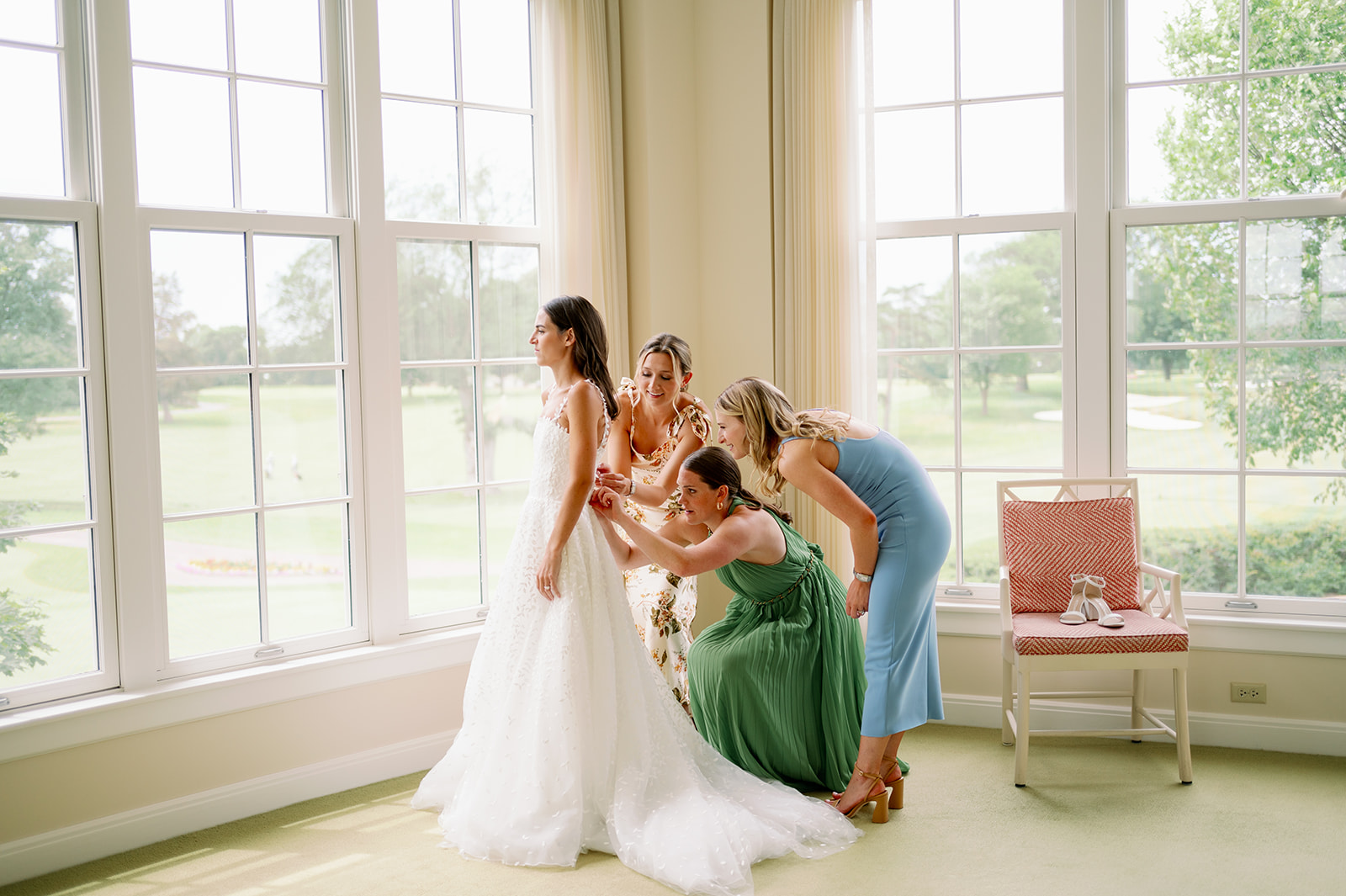 Carly's bridesmaids helping her into her wedding dress.