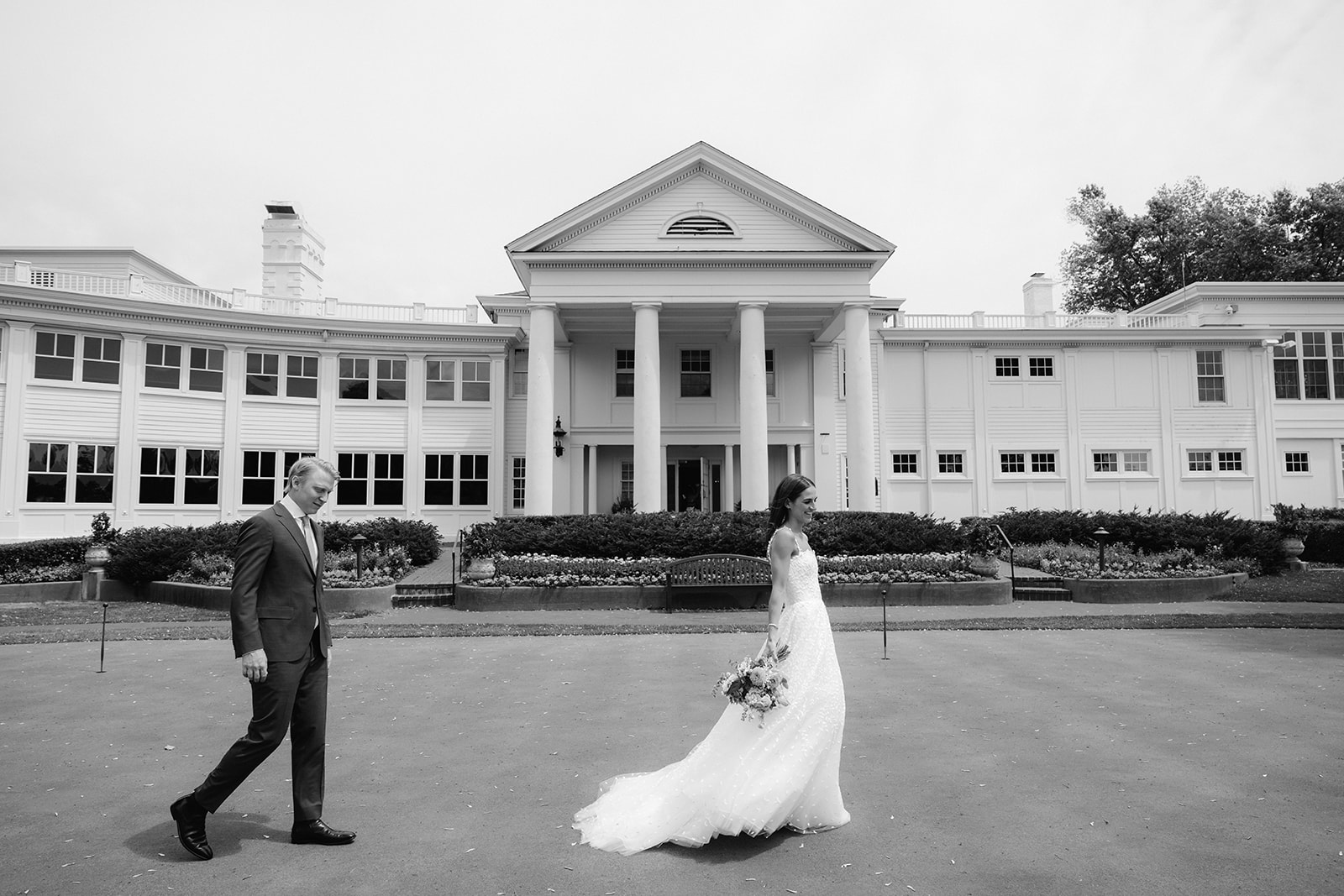 Wide shot of Carly and Todd walking on the front lawn of the Minikahda Club.