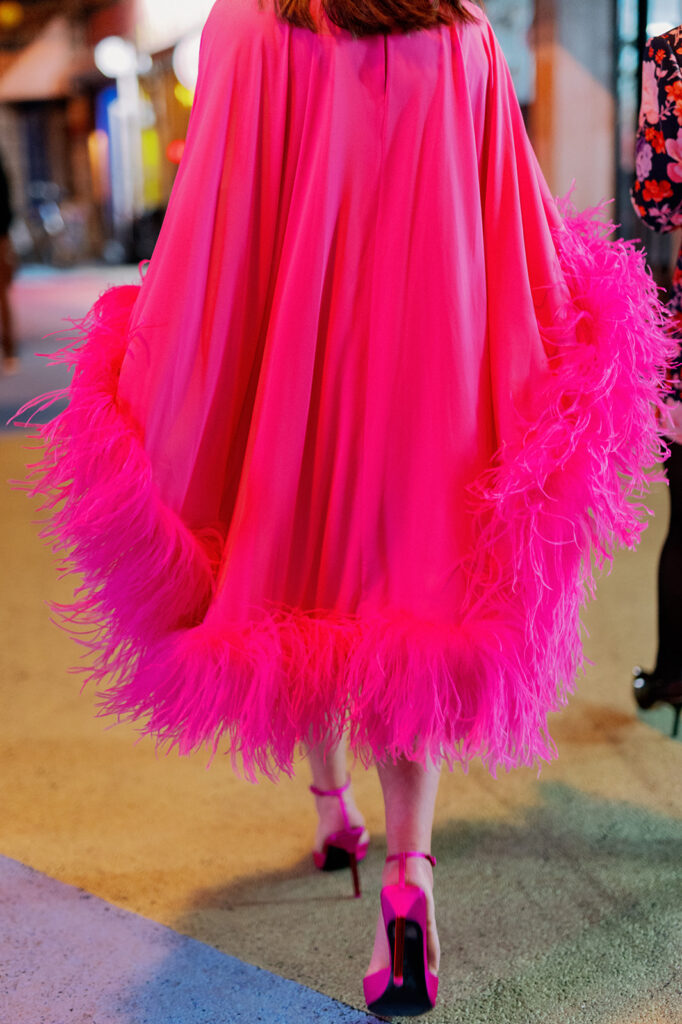 Neon pink feather-trimmed cape dress.