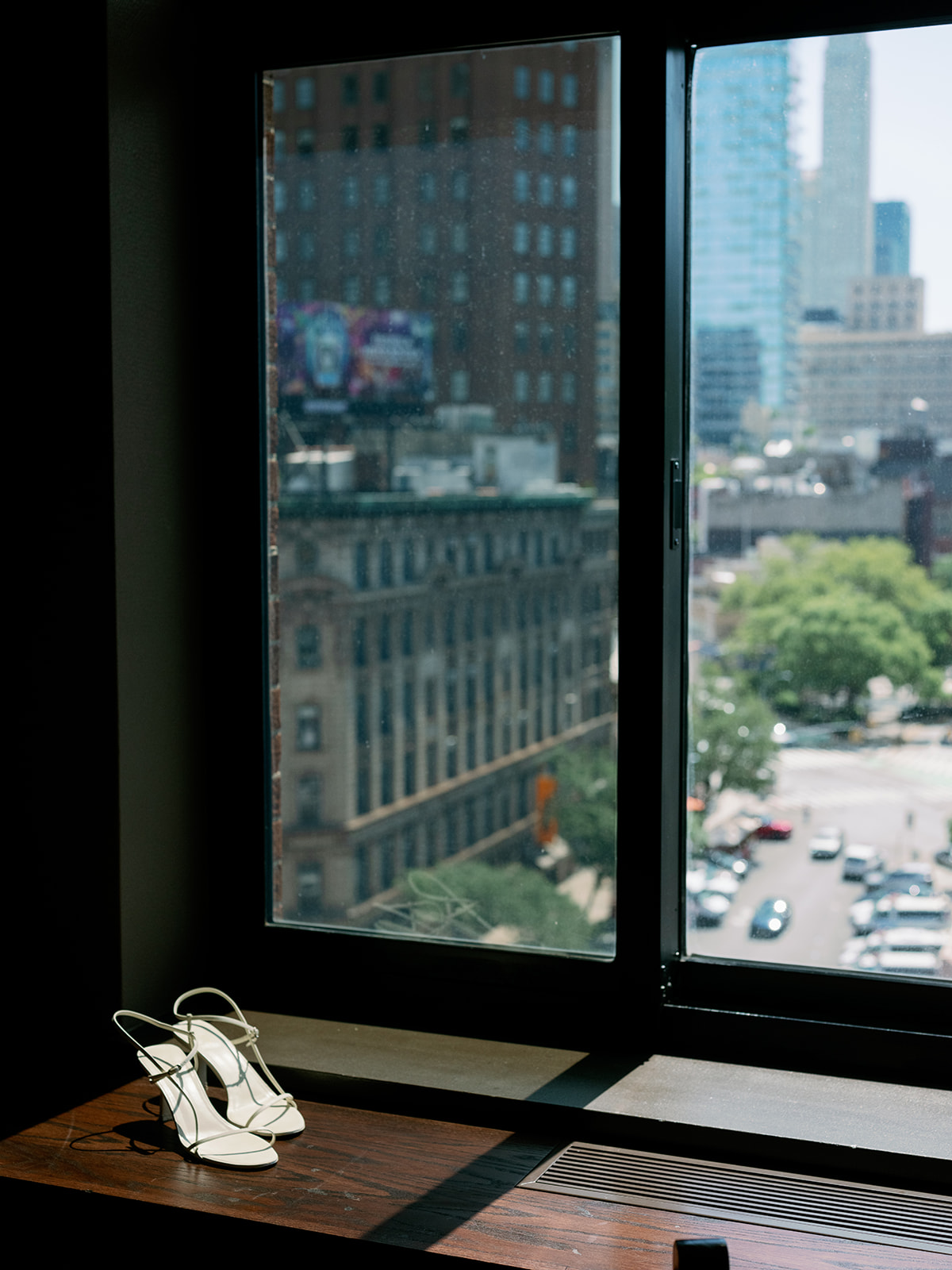 City views frame elegant white bridal shoes on a window sill, capturing the essence of a New York wedding moment.