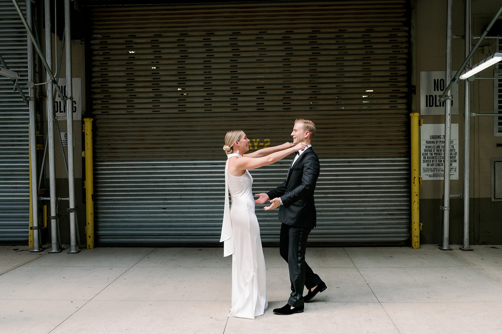 Heartwarming first look: Bride and groom walk toward each other, arms extended, ready for a hug in front of a black garage at Tribeca Rooftop.