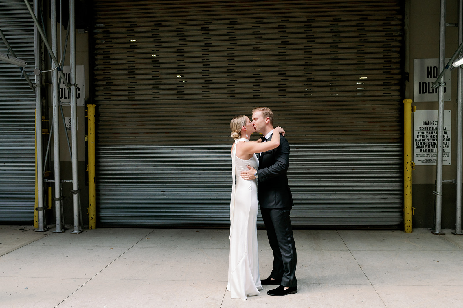 Bride and groom share a tender moment in front of a black garage at Tribeca Rooftop on their New York wedding day.