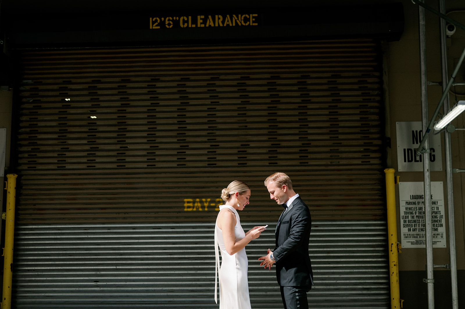Bride and groom share private vows in front of a black garage near Tribeca Rooftop. 