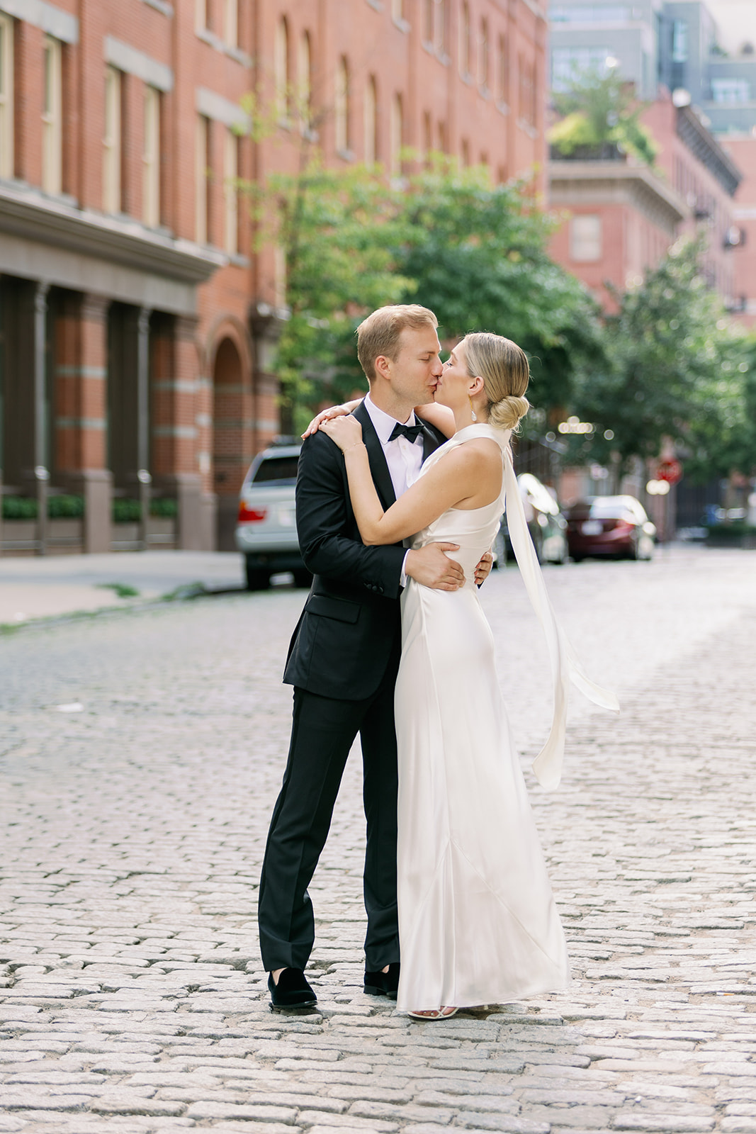 Bride and groom share a kiss on a cobblestone street in the West Village, a beautiful moment in their New York wedding portrait.