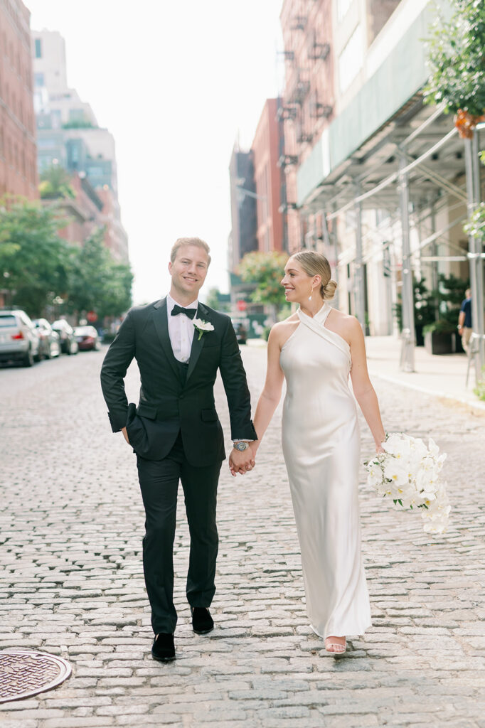 West Village bride and groom walk on a cobblestone street, captured by New York wedding photographer Katherine Marchand.
