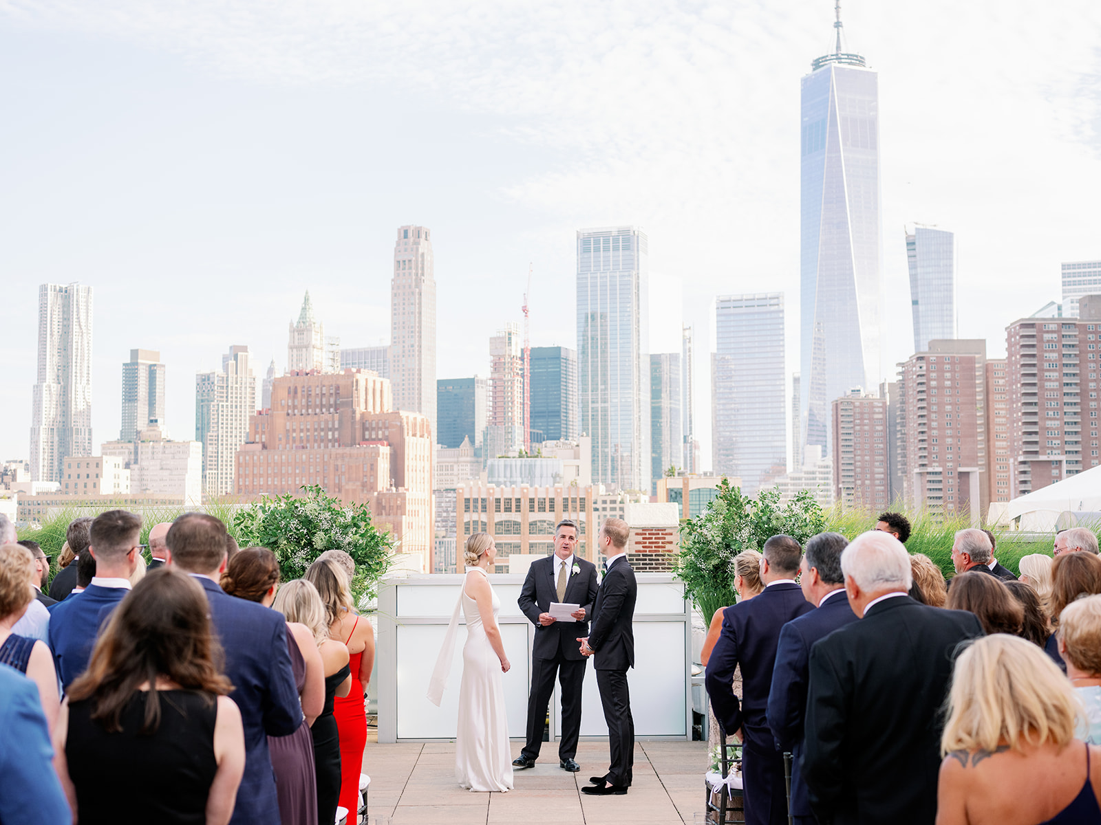 Tribeca Rooftop wedding captures the bride and groom at the altar, guests seated, against a backdrop of breathtaking city views.