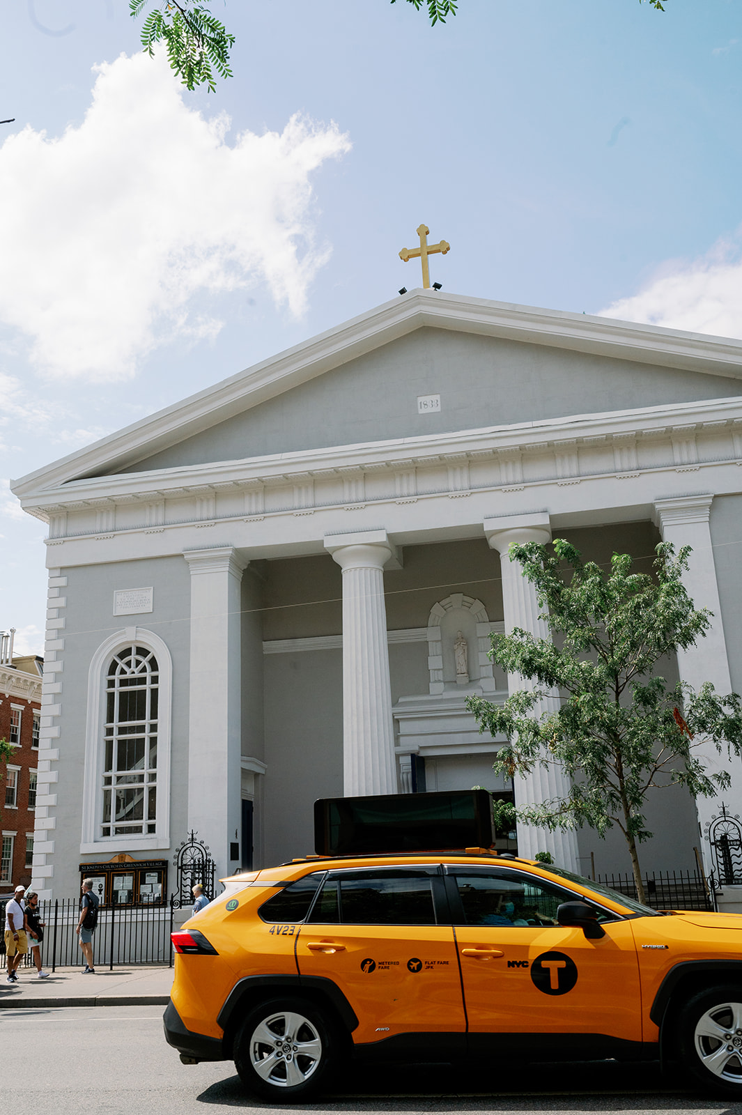 Front view of St.Joseph's Church in Greenwich Village, New York with a yellow taxi driving by. 