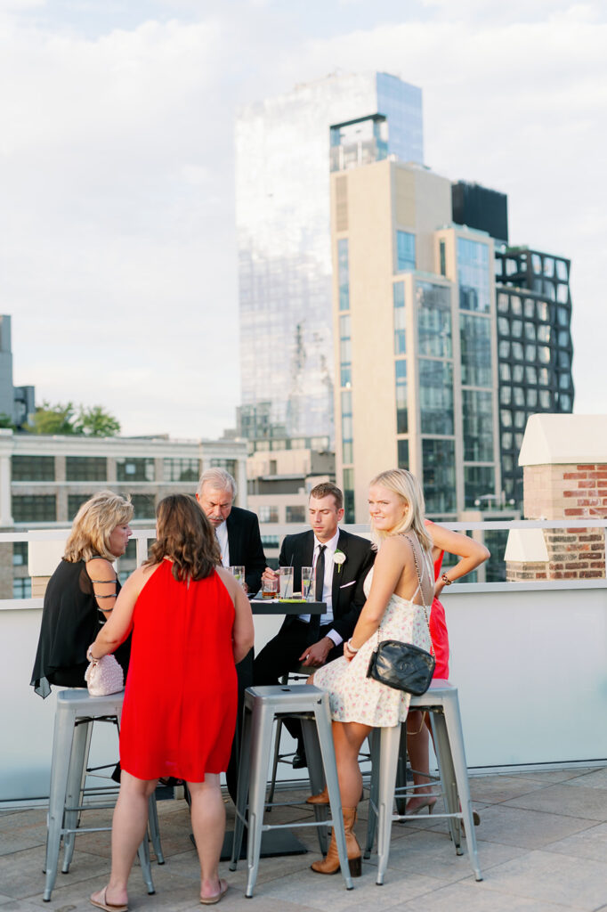 Tribeca Rooftop wedding cocktail hour captures guests enjoying the celebration with the iconic New York City skyline as their backdrop.
