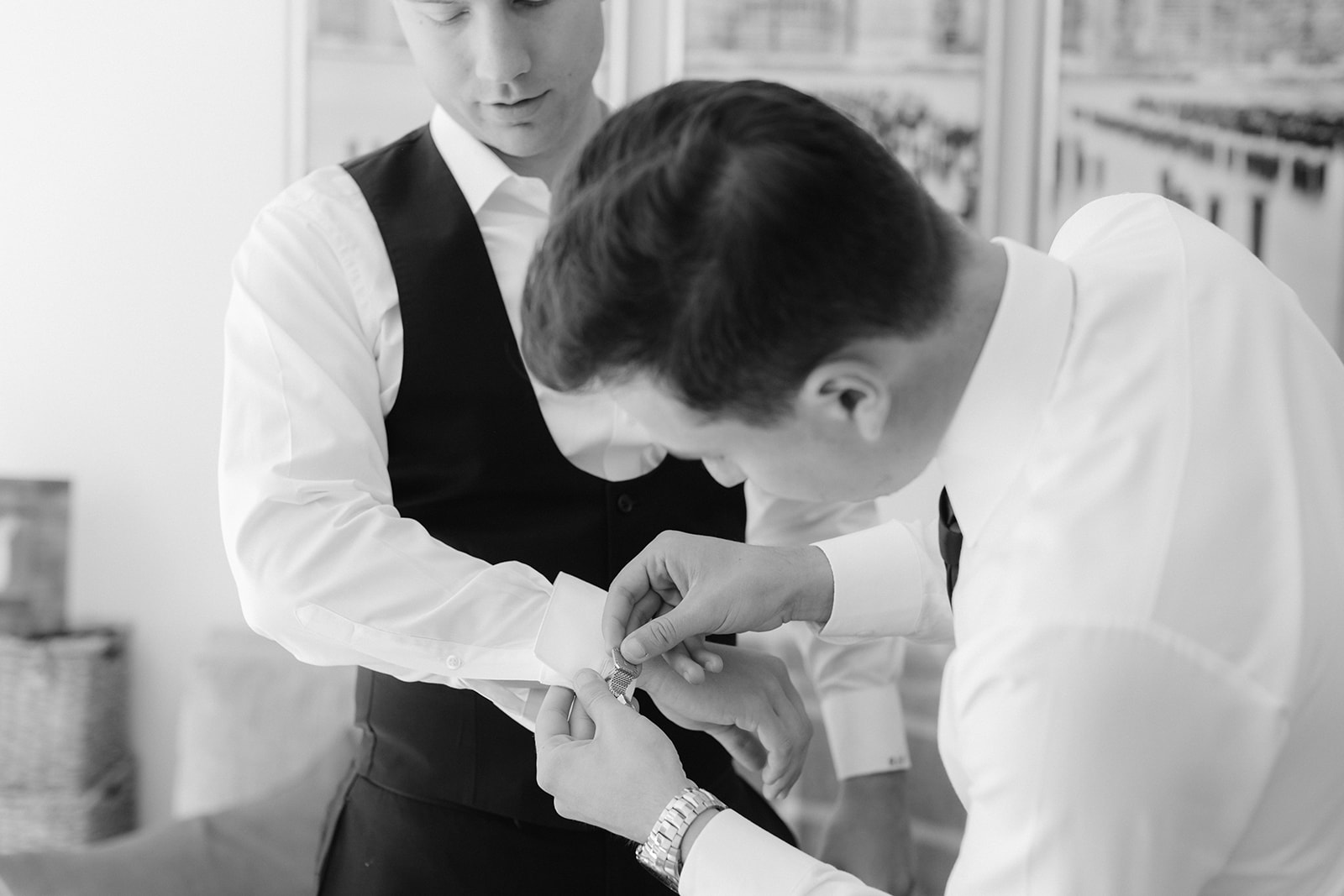 Groomsman assist the groom with cuff links while getting ready.
