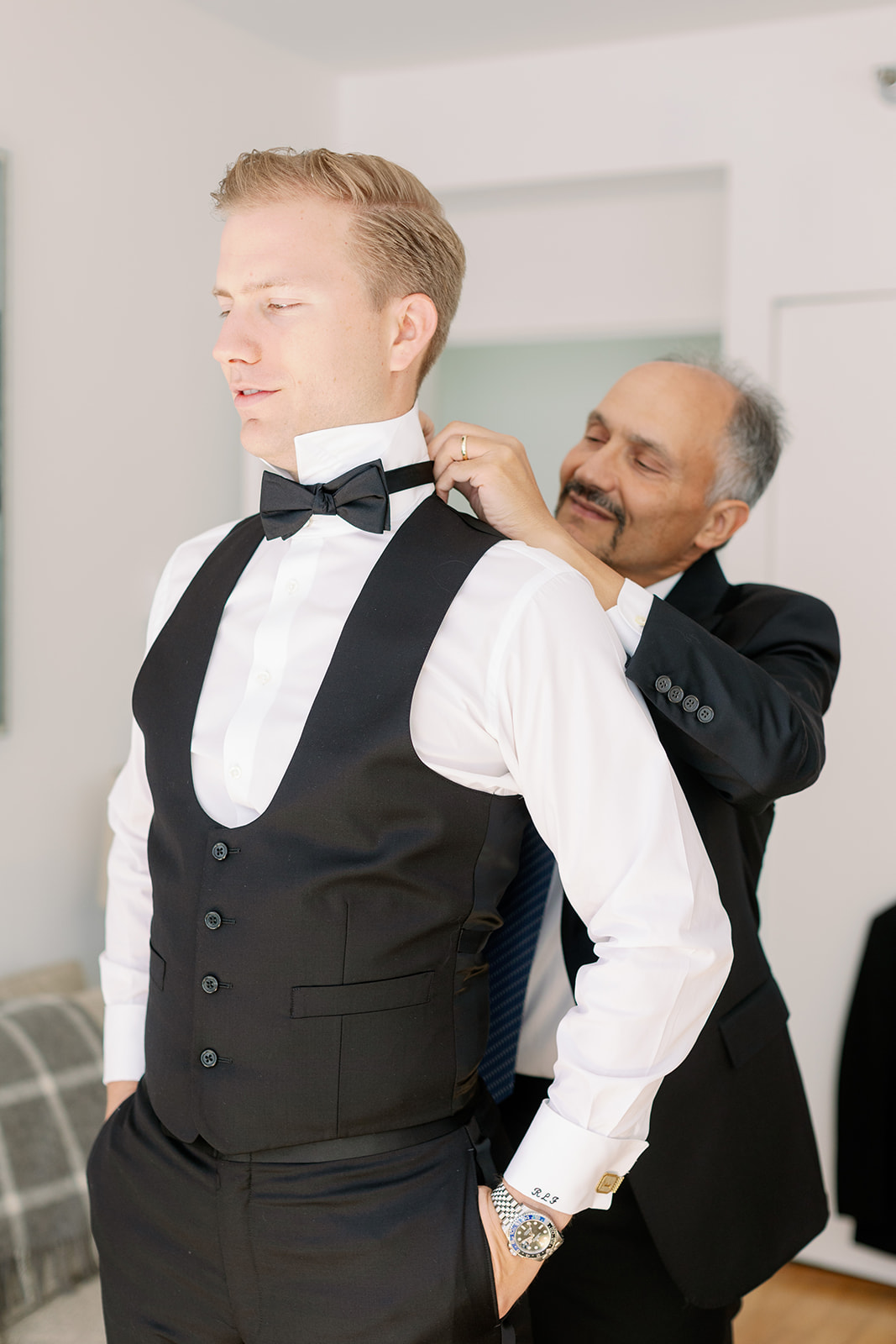 Groom gets ready, captured in a candid portrait, as his father helps with the bowtie in a New York wedding moment.