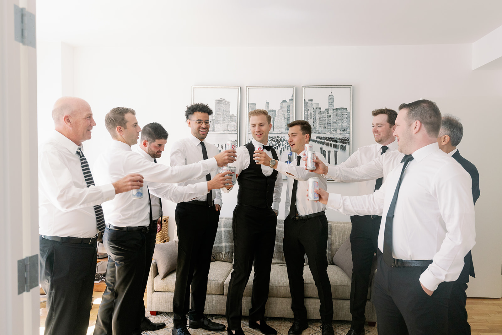 Groom and groomsmen, joined by dads, raise beer toasts post-getting ready. 