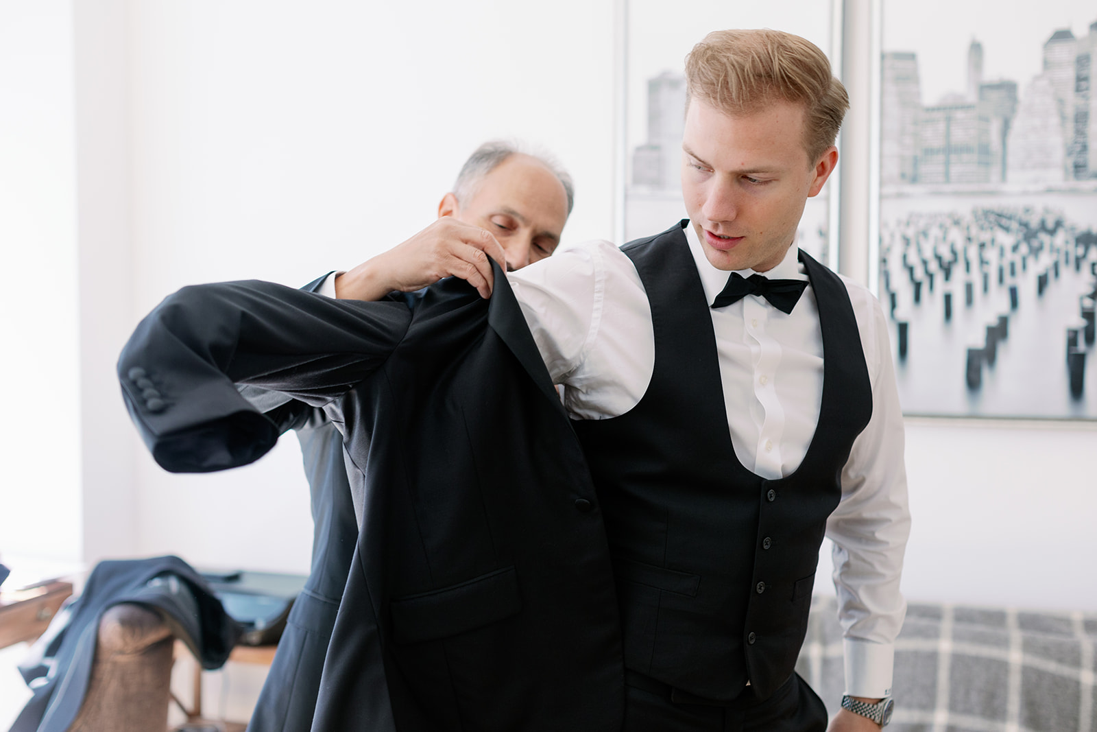 Groom getting ready, a heartfelt moment with his father helping him into the suit jacket in this New York wedding capture.