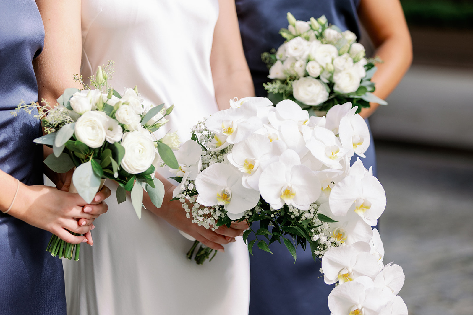 Bride and bridesmaids hold white bouquets in a stunning up-close detail shot, a beautiful New York wedding moment.