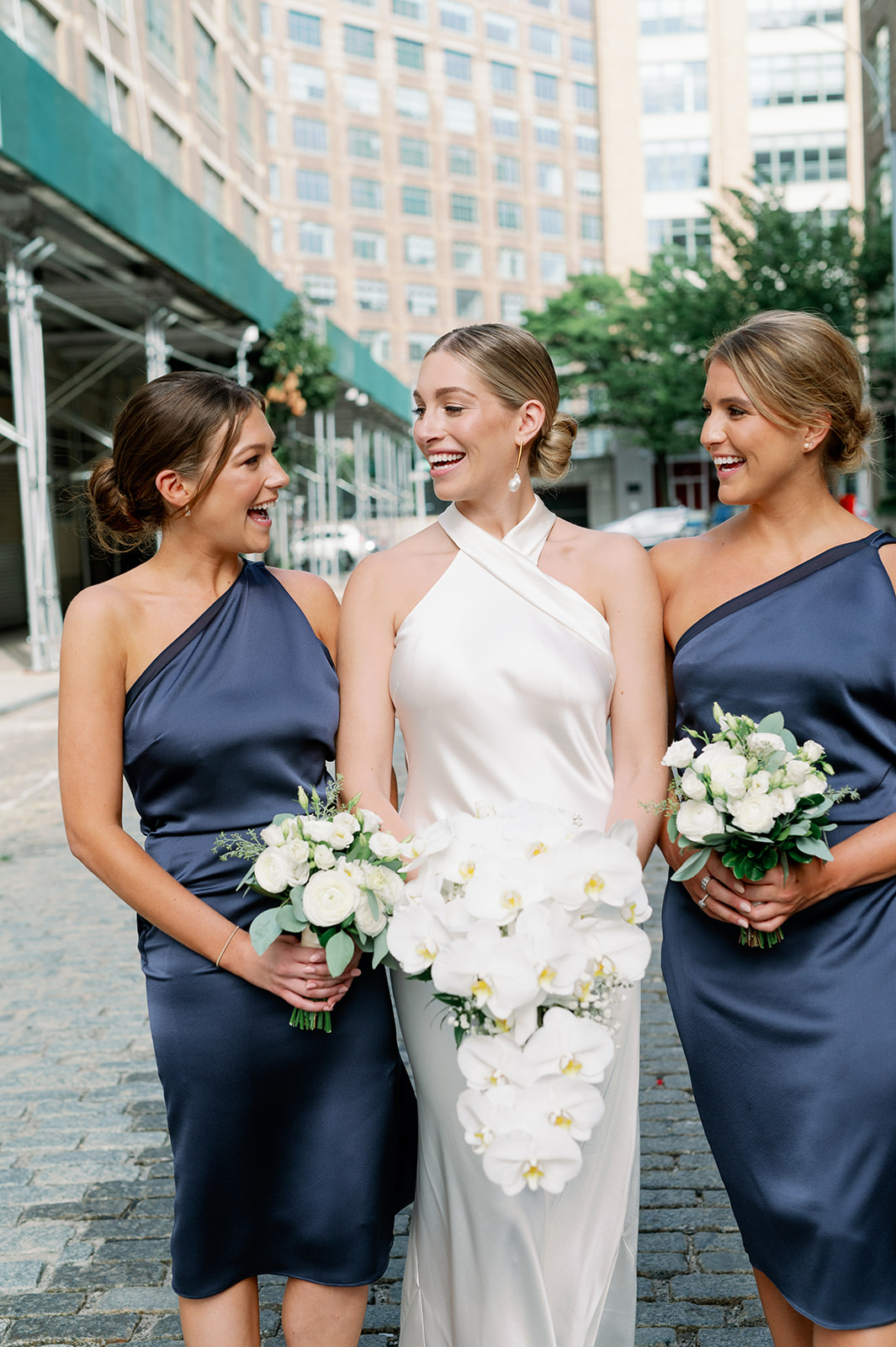 Tribeca Rooftop bride and bridesmaid candid portrait, featuring navy blue bridesmaid dresses in this New York wedding celebration.