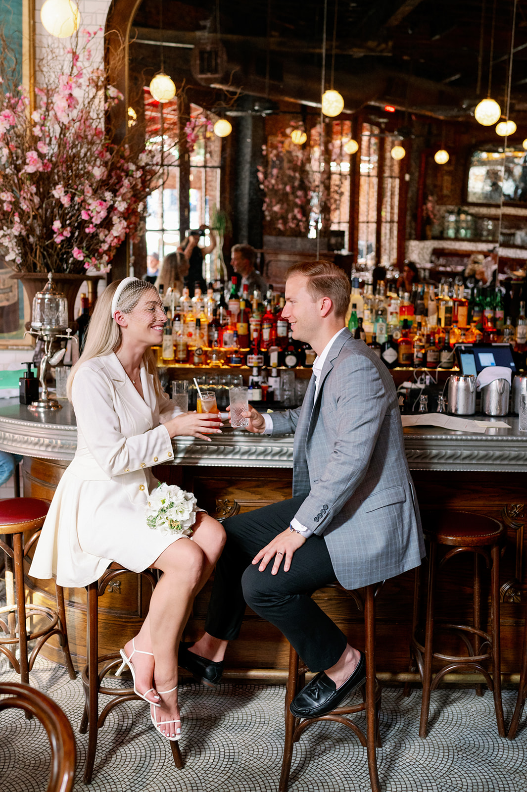 Bride and groom share smiles and a drink in a NYC bar, celebrating their intimate ceremony.