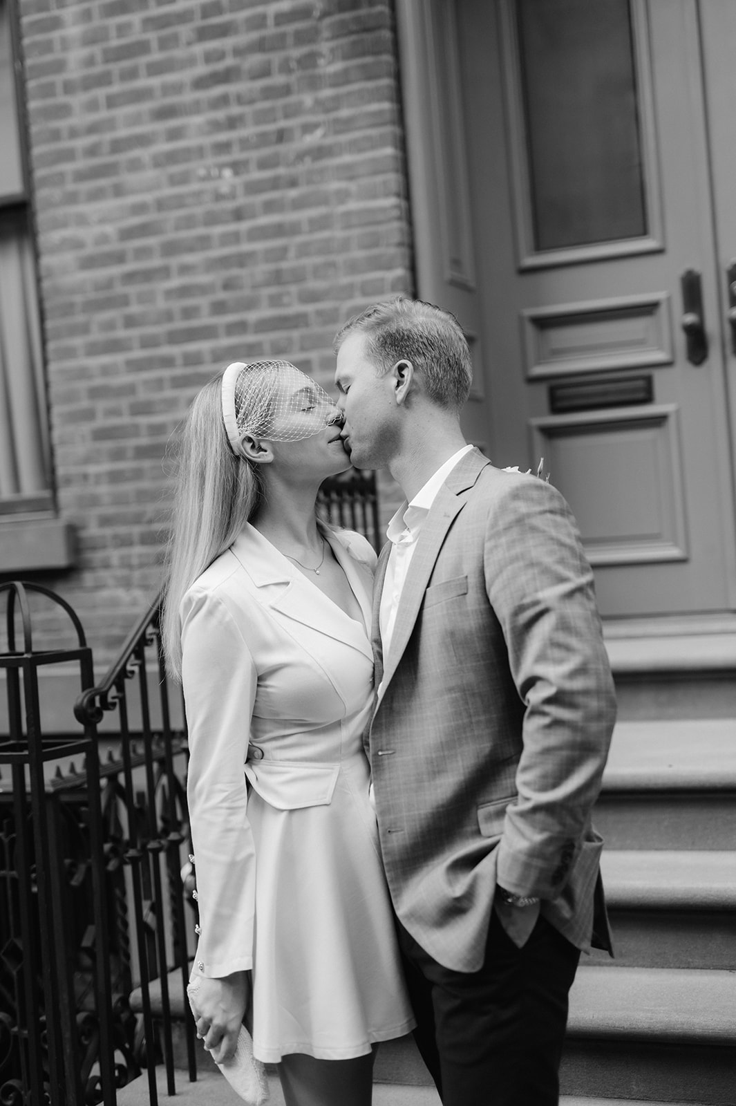 Bride and groom share a timeless black & white kiss in front of a West Village brownstone, after their romantic New York City wedding ceremony. 