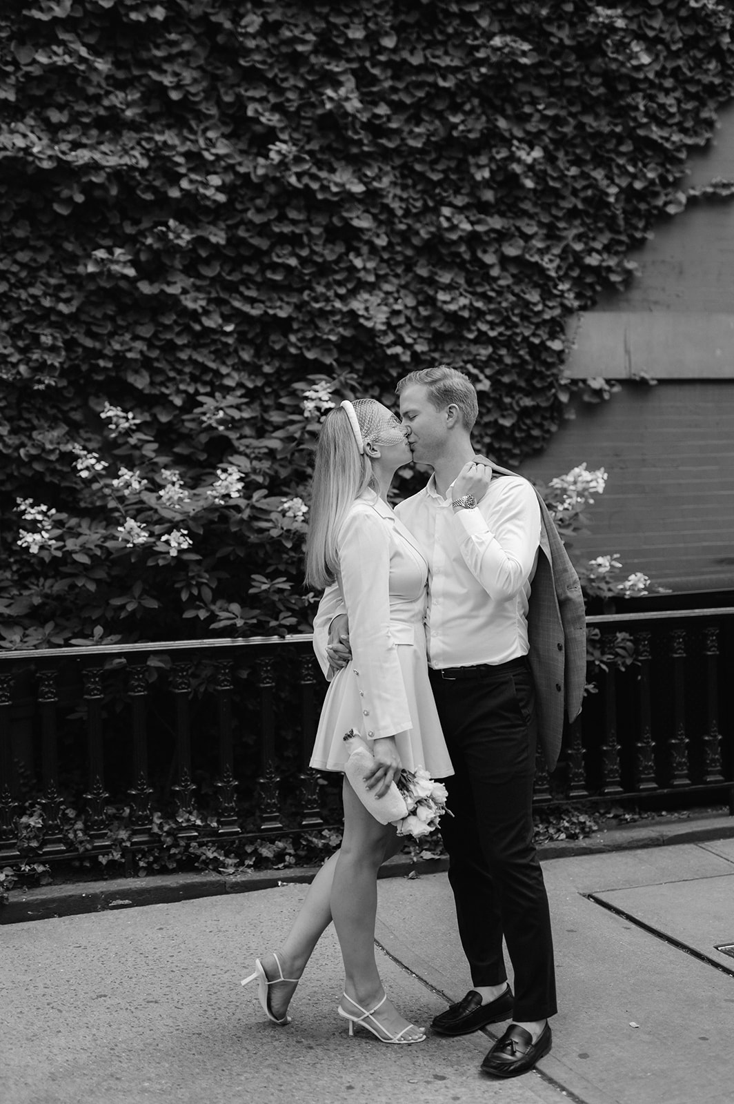 Bride and groom share a timeless kiss in Greenwich Village, against a backdrop of a brownstone draped in greenery