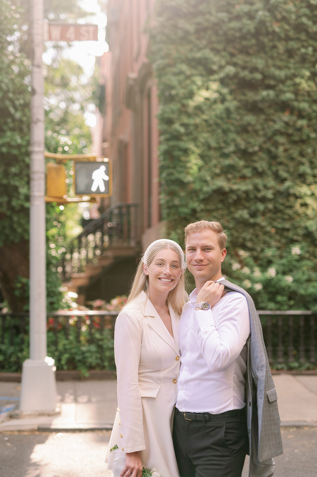 Bride and groom capture classic romance in Greenwich Village street, a brick brownstone draped in greenery providing an iconic New York backdrop.