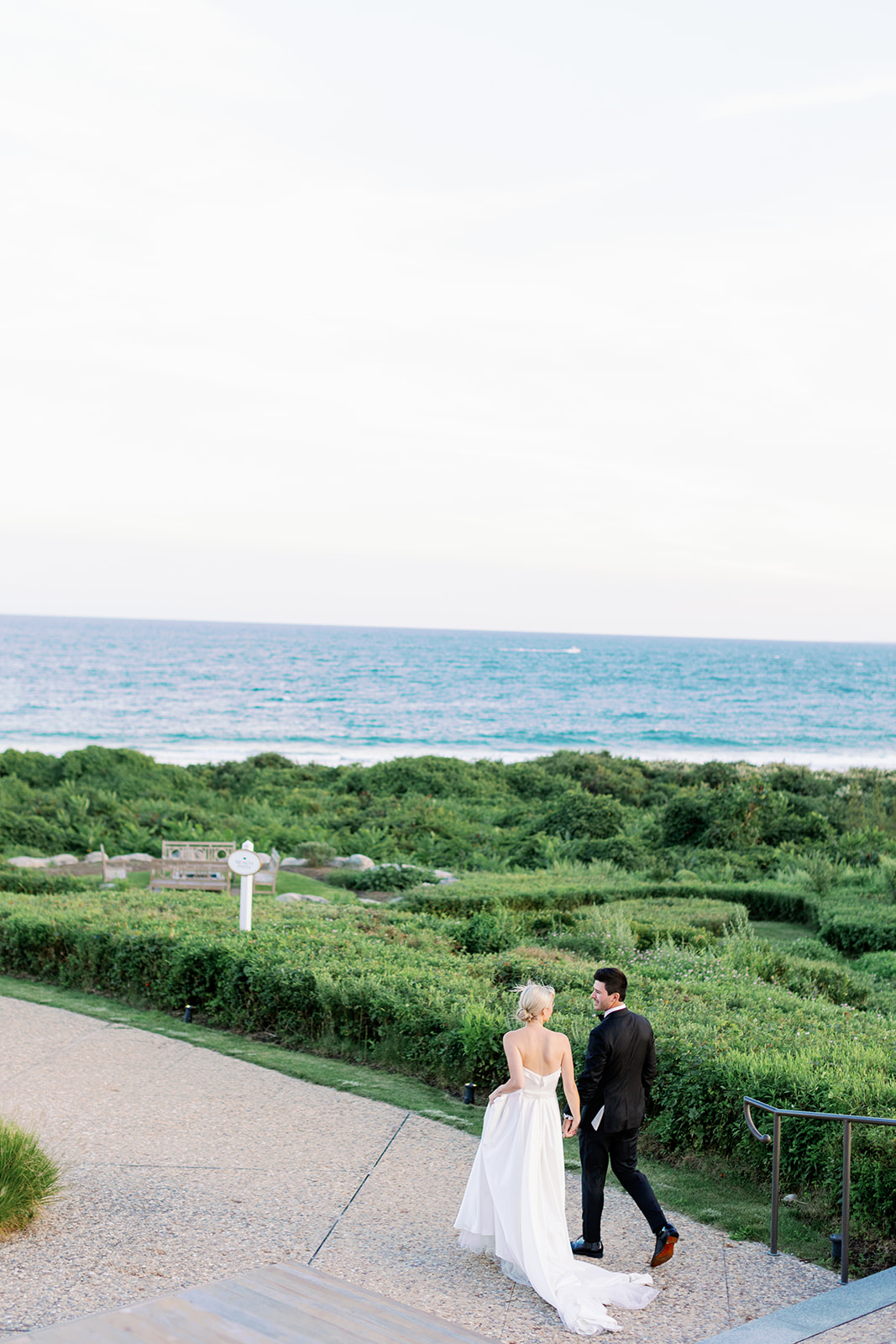 Bride and groom walking towards the water at Ocean House in Rhode Island.