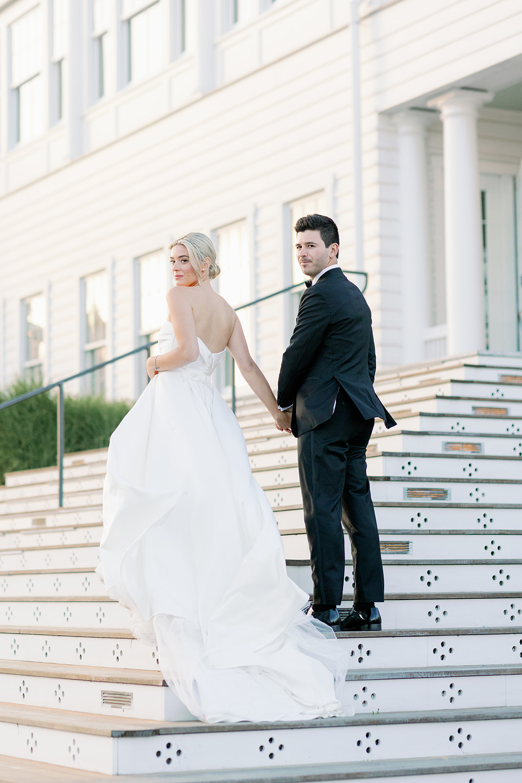 Bride and groom walking up the steps of Ocean House. 
