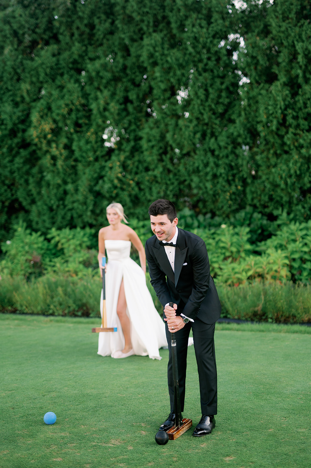 Bride and groom playing croquet on the lawn of Ocean House. 