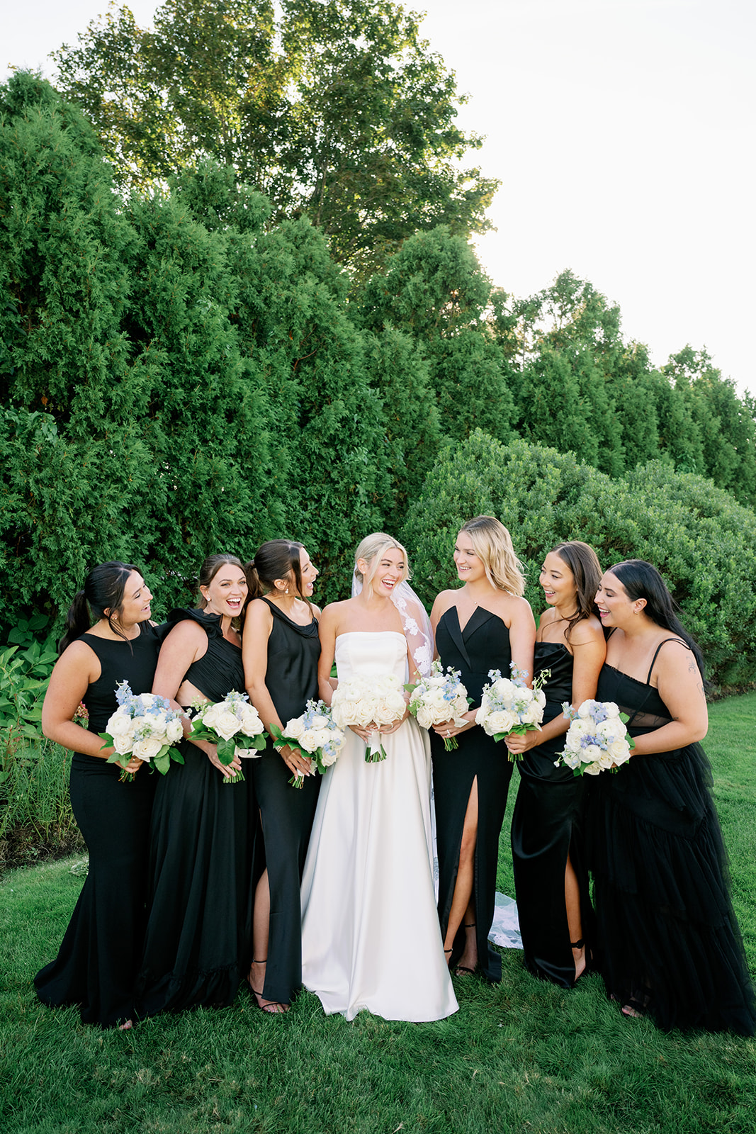 Candid bride and bridesmaid portrait with mismatched black bridesmaid dresses.  