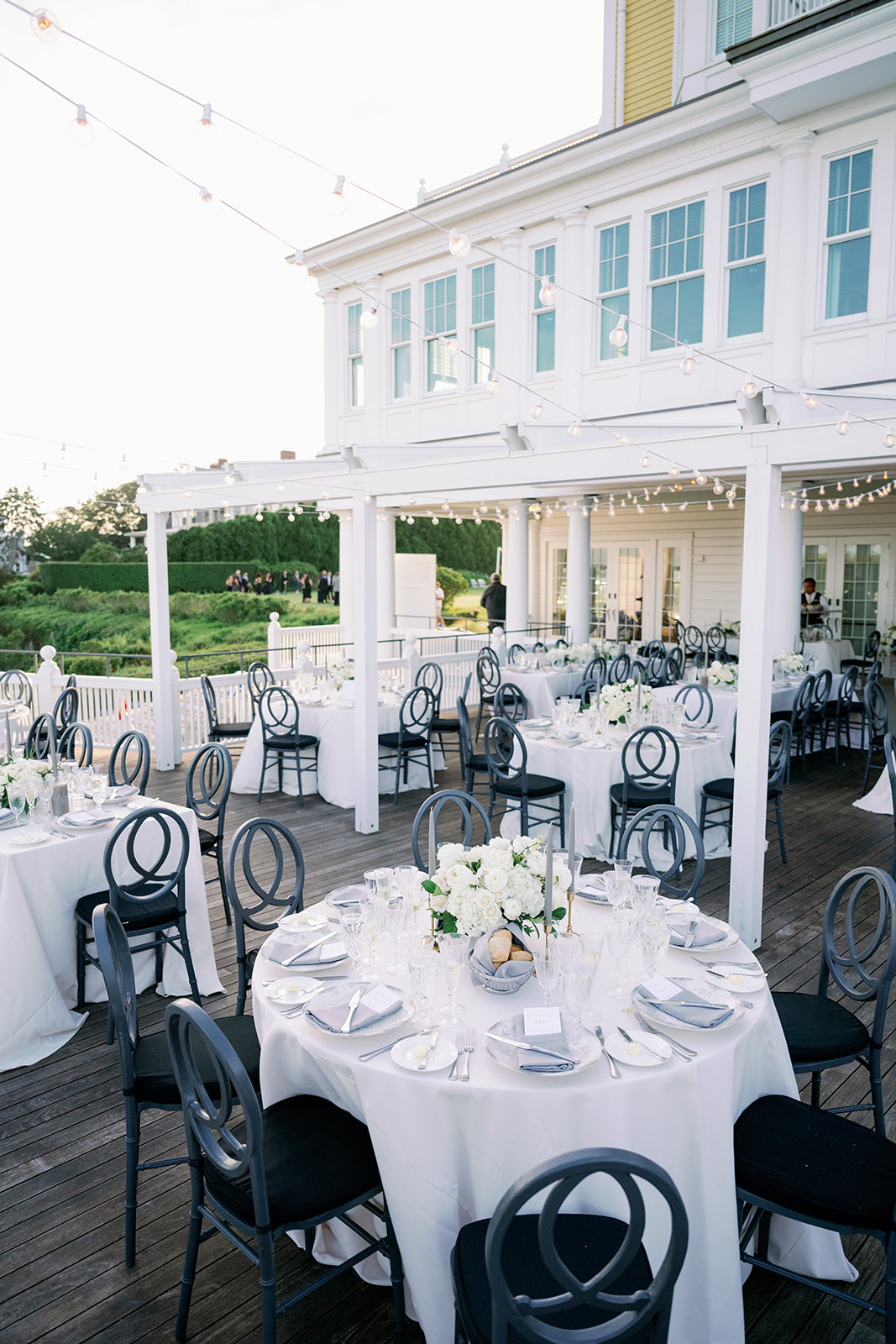 Ocean House wedding outdoor dinner with white tables and black chairs. 