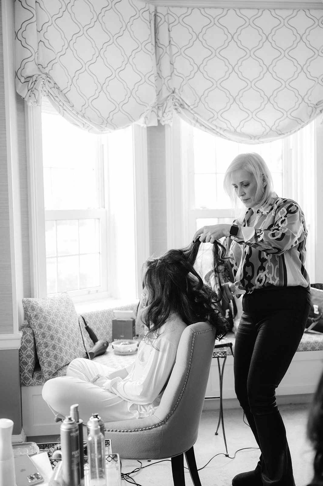 Bride getting her hair done in front of a large window at Pine Hollow Country Club.