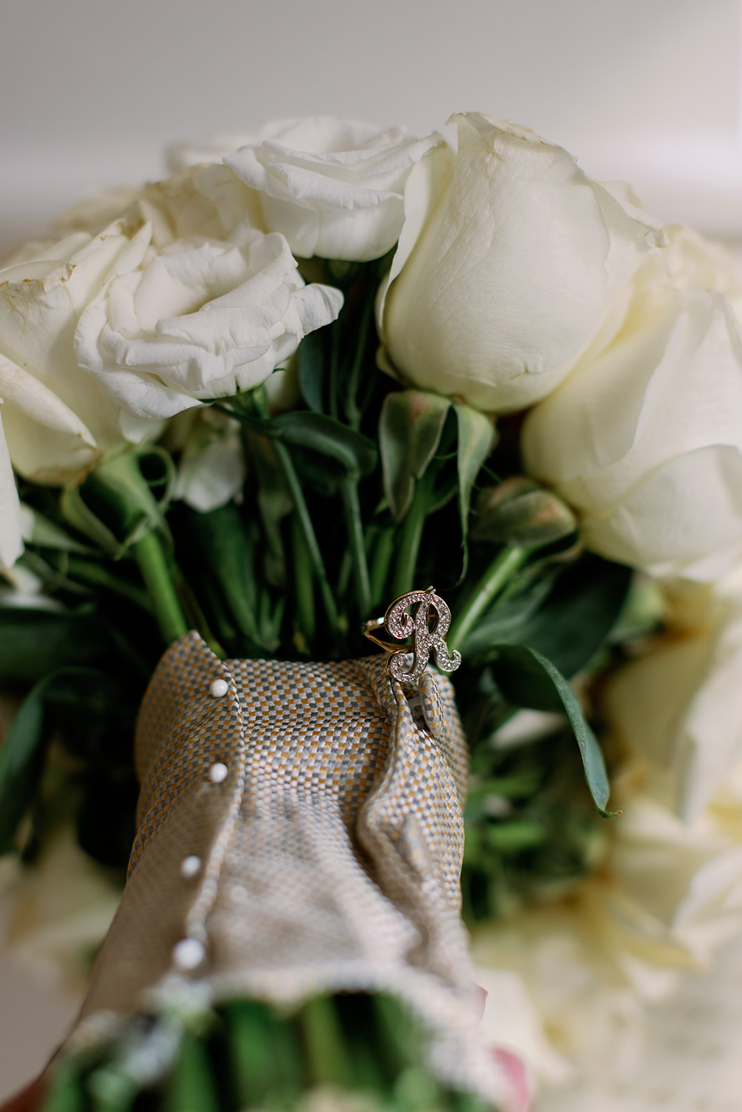 Up close detail shot of bride's white rose bouquet with a burlap wrap. 