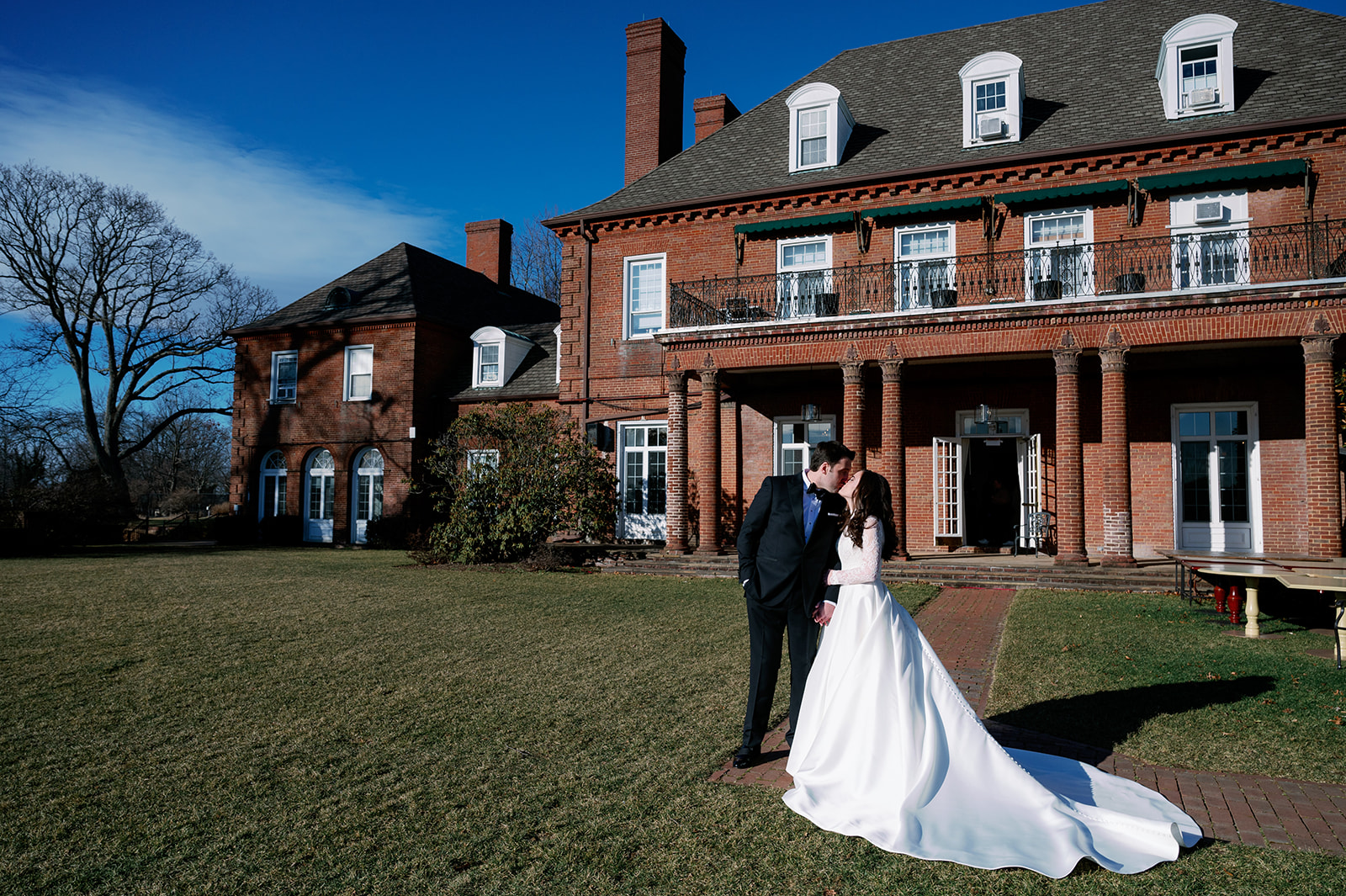 Bride and groom kissing in front of their New York wedding venue Pine Hollow Country Club.